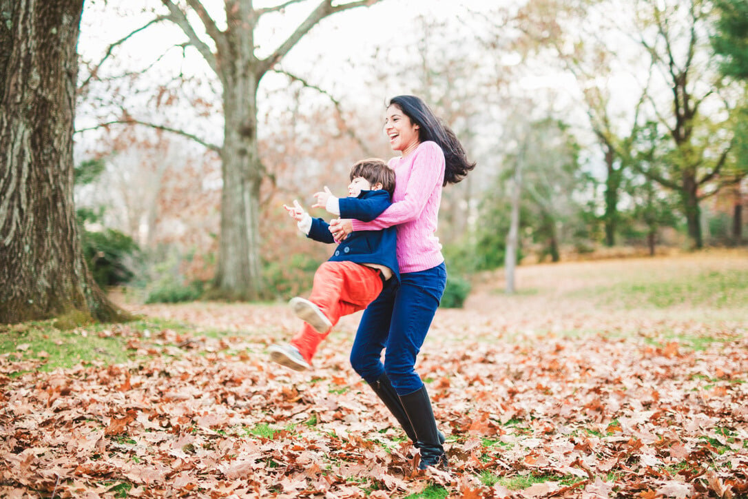 Smiling mom playing with her young son outdoors on an autumn day